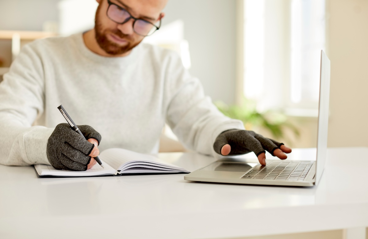 Man writing and typing, while wearing hand supports