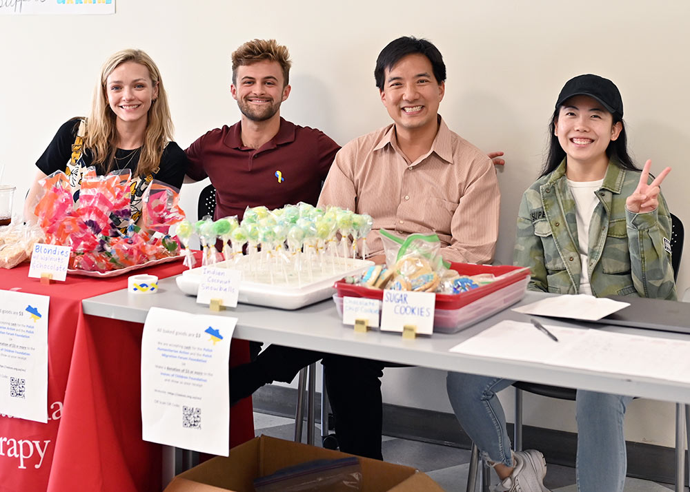 Photo of four people sitting at bake sale table
