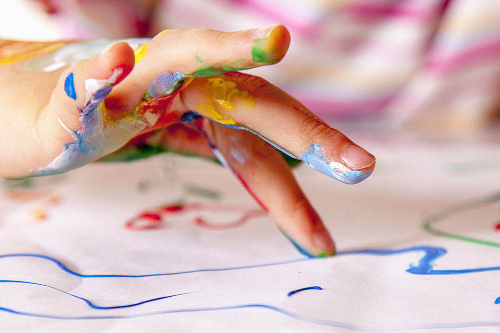 Close-up photo of child's messy hand doing finger painting