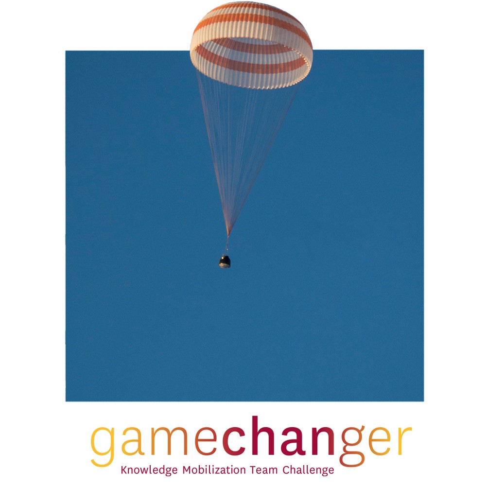 Cropped photograph of space capsule returning to earth with extended orange and white parachute.