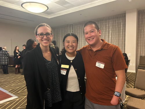 Mercy Deng stands between two clinical faculty members, one woman and one man. They are all smiling at the OTAC conference.