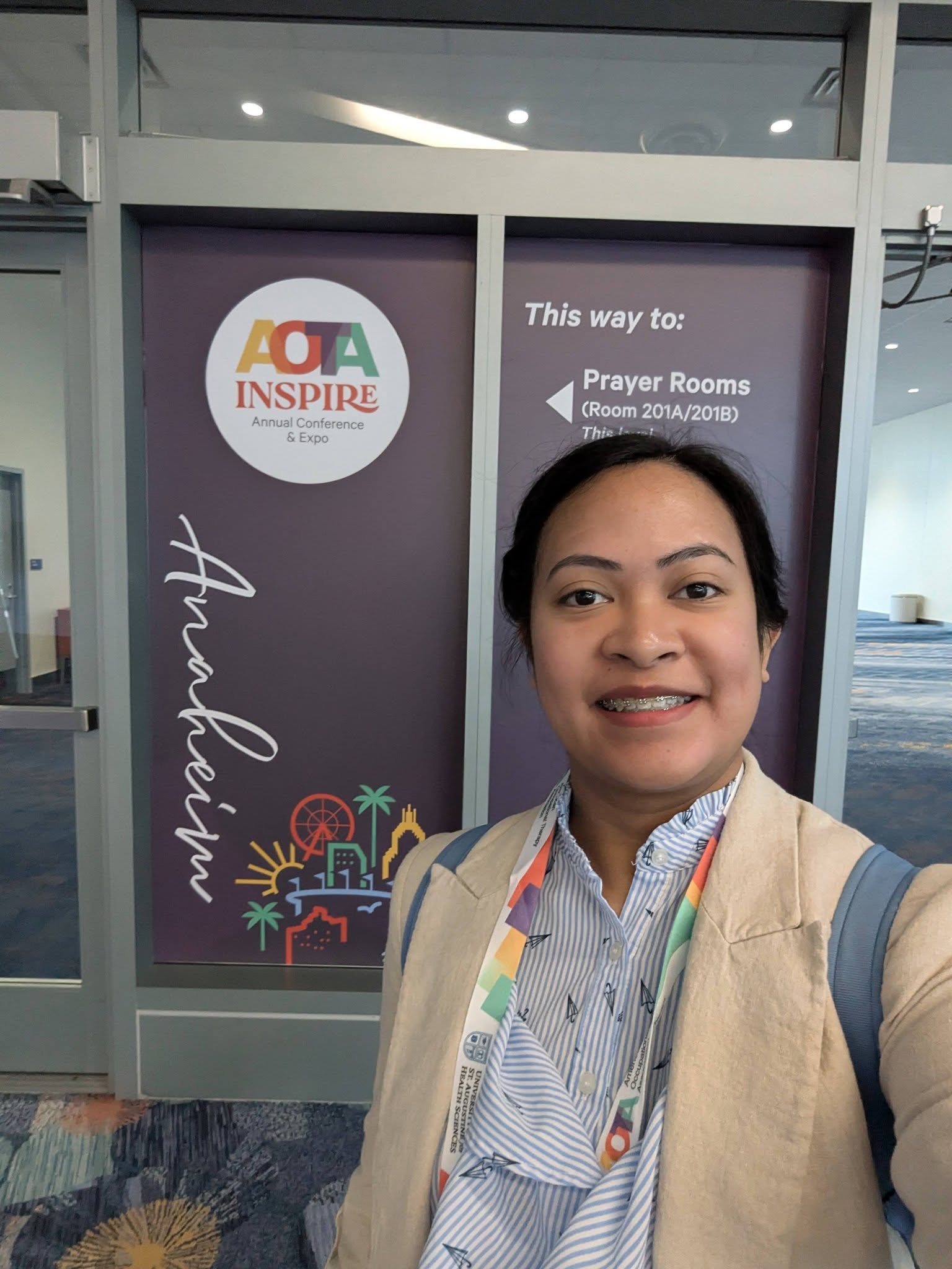 Nicole posing for a selfie in front of an AOTA sign