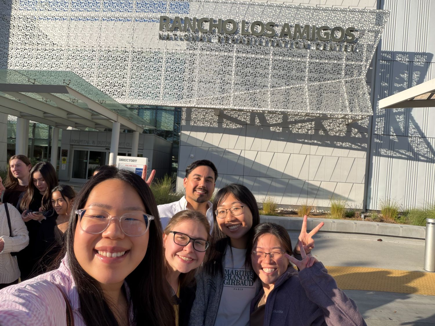 Trinity posing in front of a rehab hospital with classmates