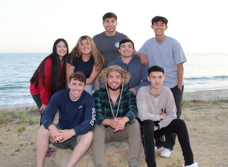 Eight young adults smiling for a picture at the beach