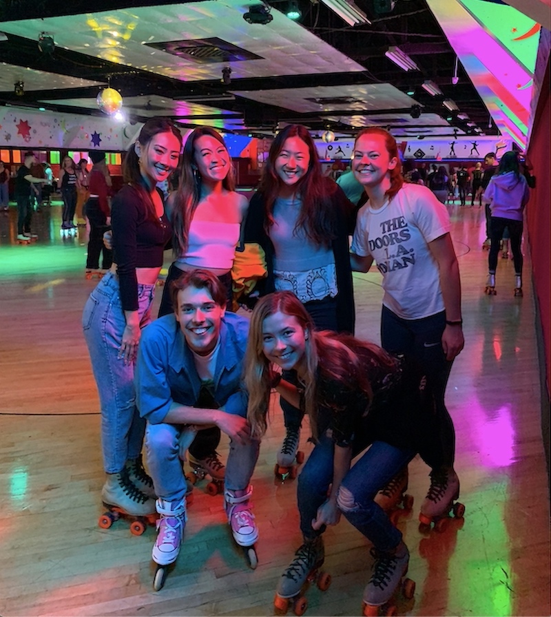 Six bachelor’s to master's students wearing roller-skates at a neon roller rink